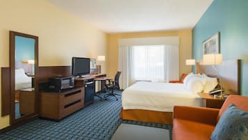 A hotel room with a bed, desk, television, and a view of the outdoors.