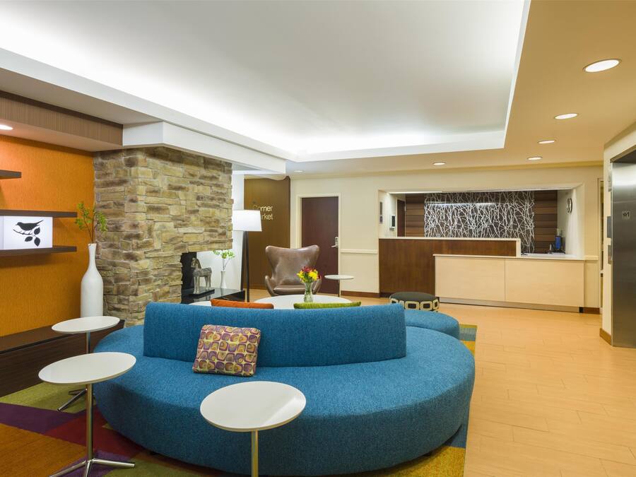 A modern living area with a blue sofa, white round tables, a stone accent wall, and a kitchen in the background.