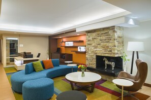 A modern lounge area with a stone fireplace, blue sofas, a coffee table, and a lamp. - Best Western Allentown Bethlehem Lehigh Valley Inn & Suites (Bethlehem)