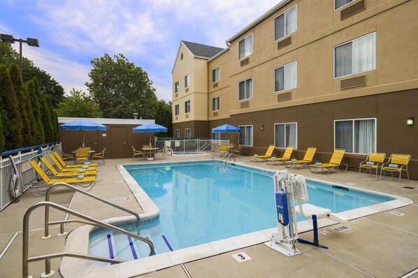 A hotel pool area with a clear pool, yellow lounge chairs, and blue umbrellas. - Best Western Allentown Bethlehem Lehigh Valley Inn & Suites (Bethlehem)