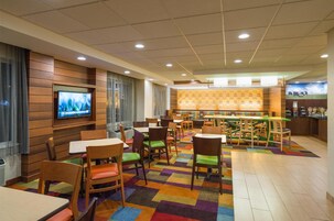 Un hall de hotel con zona de bar, varias opciones de asientos y una pantalla de televisión.
