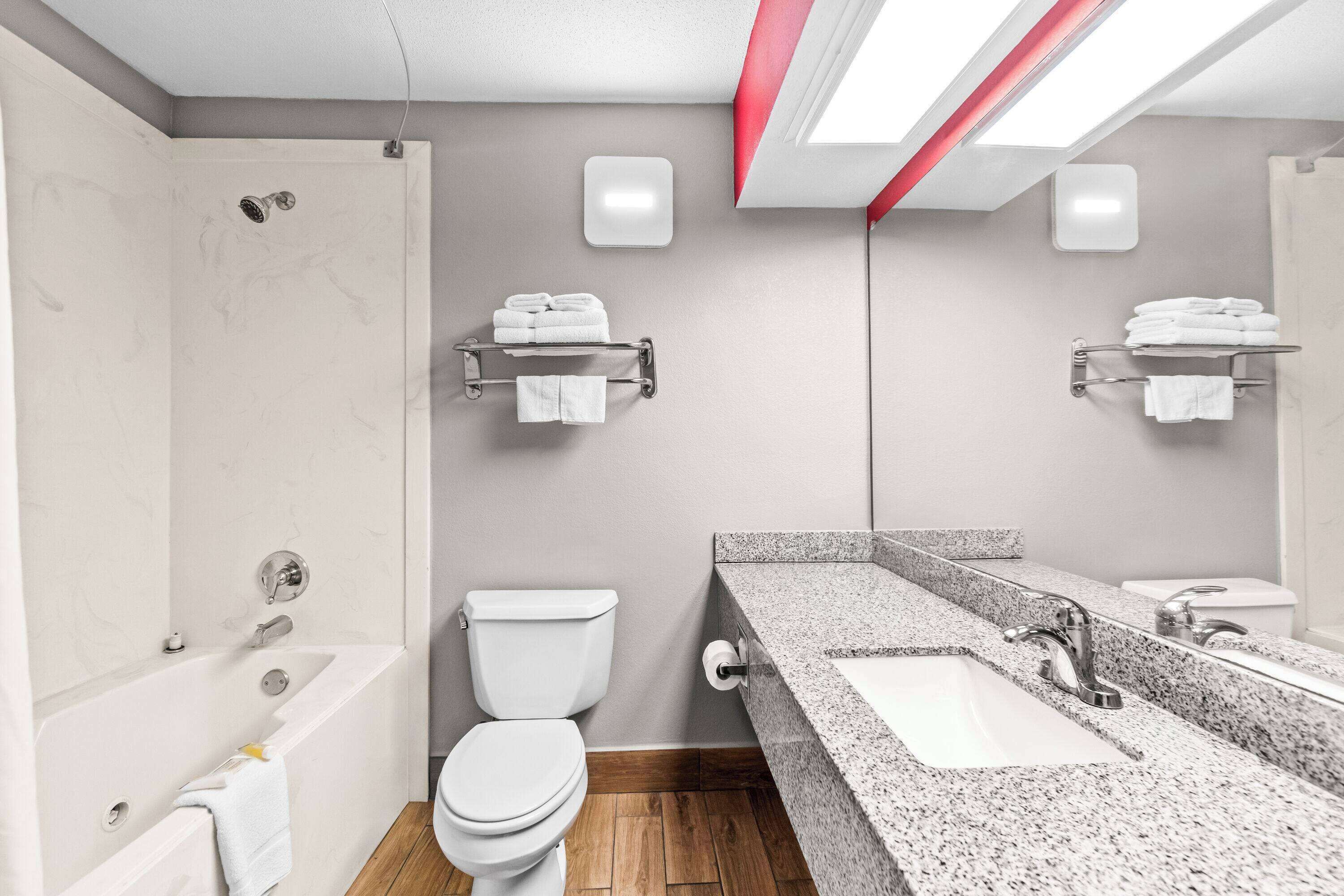 Een moderne badkamer met een badkuip, toilet en een wastafel met granieten blad.