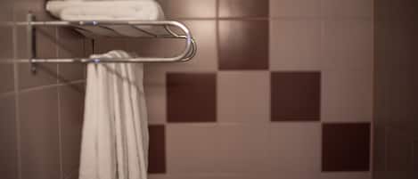 A bathroom with a towel rack holding folded towels and a rack with a towel hanging.