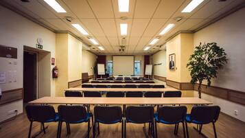 A conference room with a long table and chairs, a clock, and a plant.