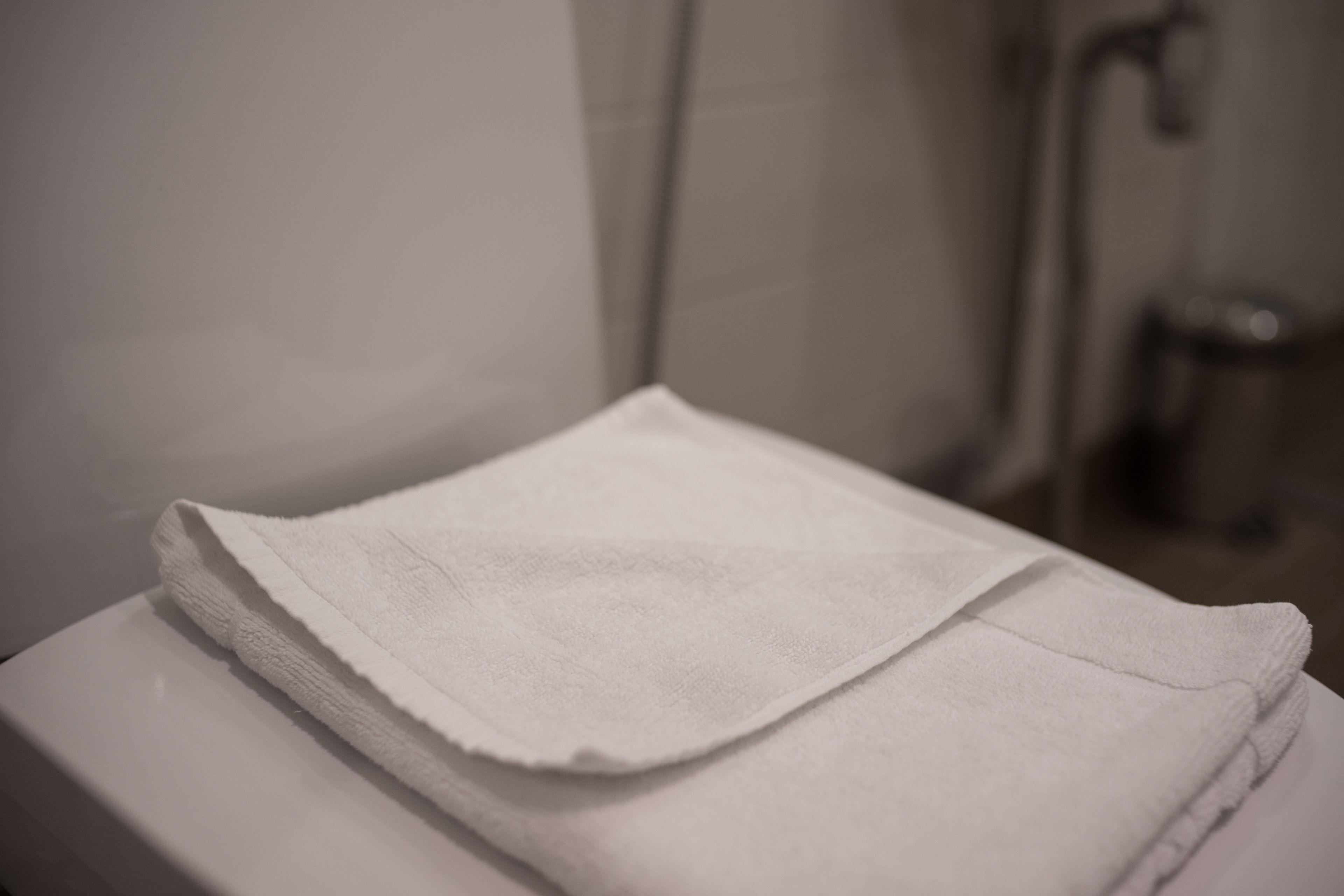 Una toalla blanca doblada sobre una superficie blanca, probablemente un lavamanos o encimera de baño.