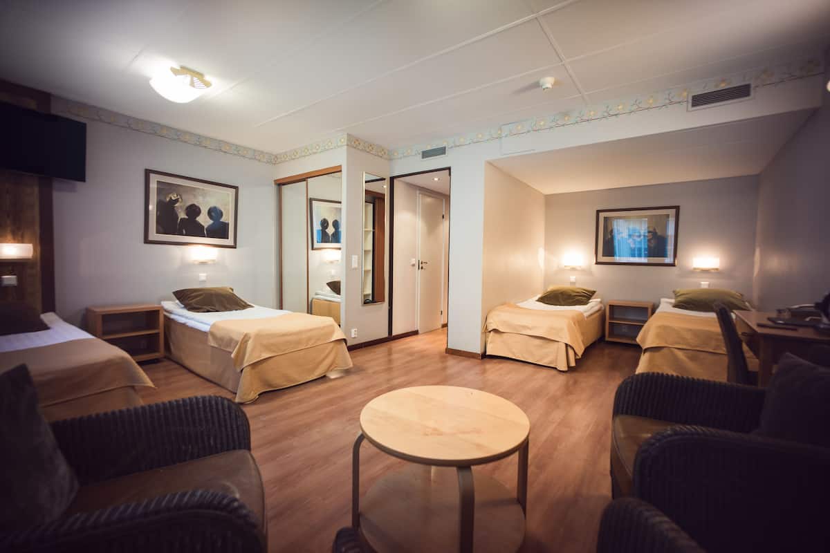 Hotellihuone, jossa on kaksi erillistä sänkyä, pyöreä pöytä ja kaksi tuolia.