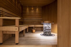 Una sauna de madera con bancos y un elemento central de piedra.