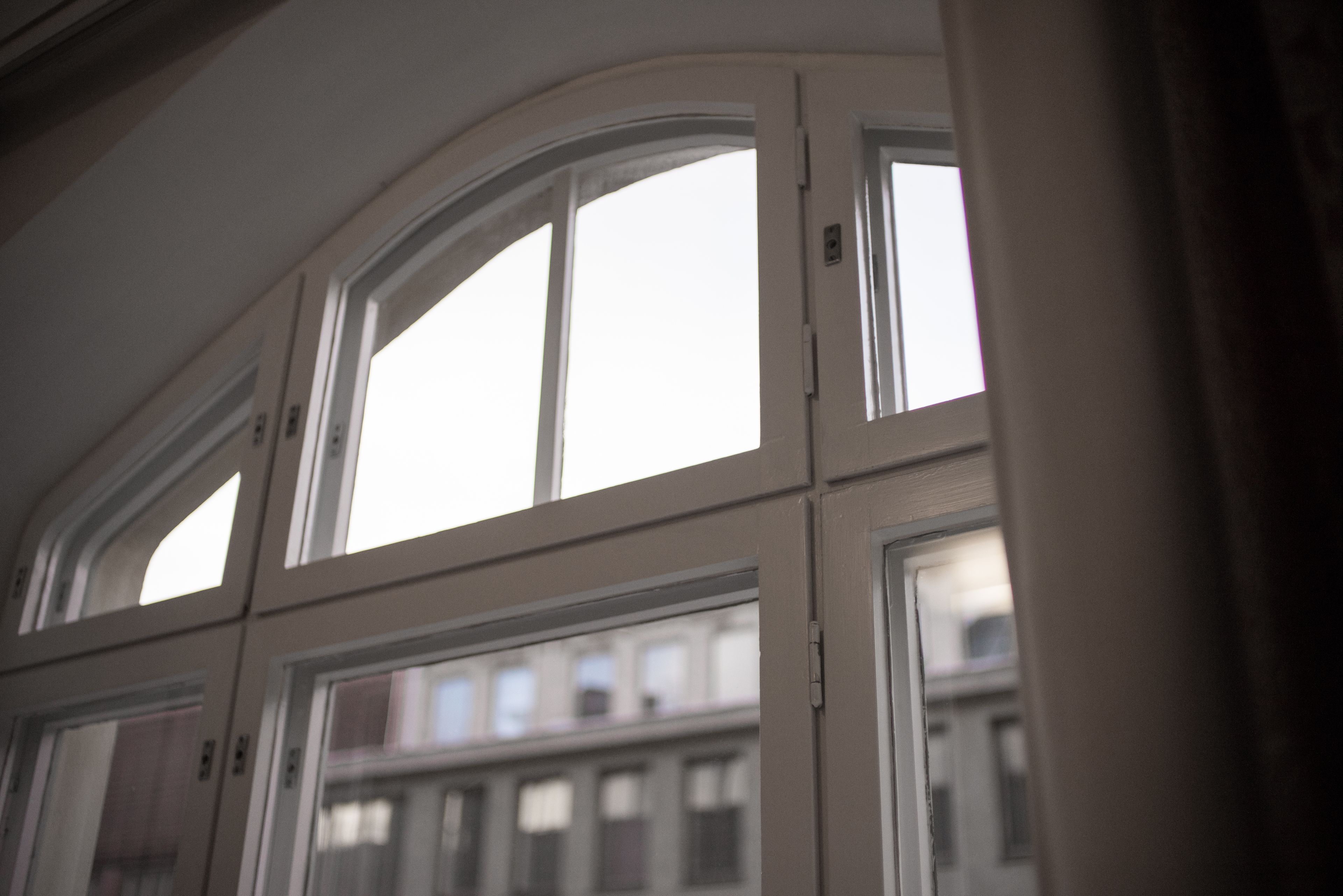 A view of a room with large arched windows and a view of buildings outside.