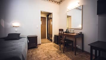 Una habitación de hotel con una cama, un escritorio con silla, un espejo y una mesita.