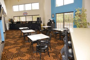 A restaurant with a breakfast corner, tables, chairs, and a patterned carpet. - Baymont by Wyndham Santee (Santee)