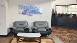 Een hal met twee leren fauteuils, een tafel met marmeren blad en een kamerbreed tapijt met patroon.