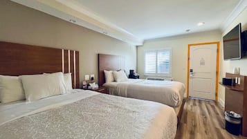 Una habitació d'hotel amb dos llits, televisió, porta i finestra amb persianes.