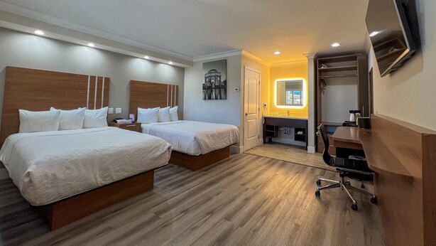 Une chambre d’hôtel avec deux lits, un bureau, une chaise, une télévision et une salle de bain.