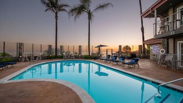 A swimming pool with lounge chairs and palm trees.