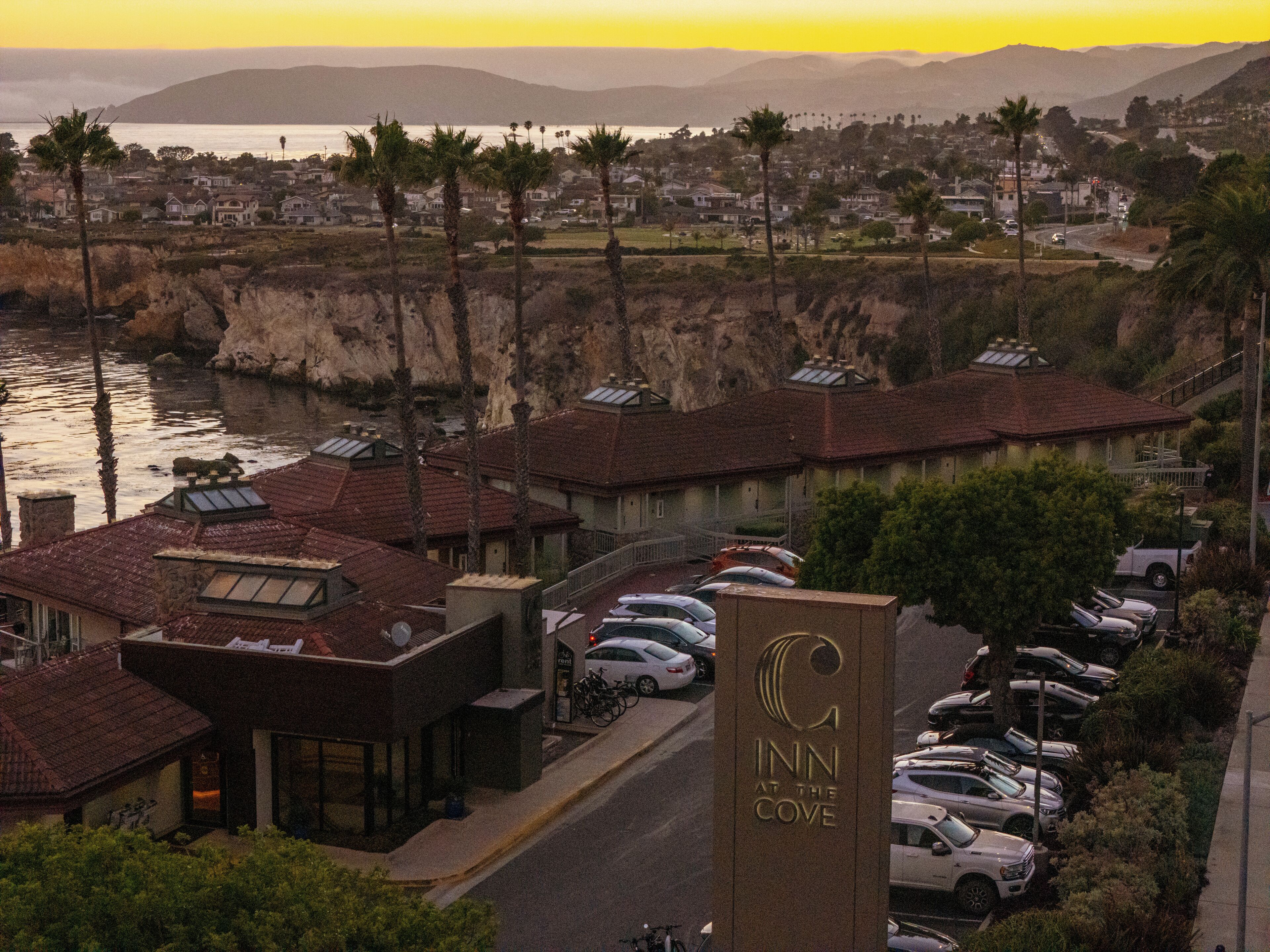 Ein Hotel mit auffälliger Beschilderung, Parkplatz und Blick aufs Meer.