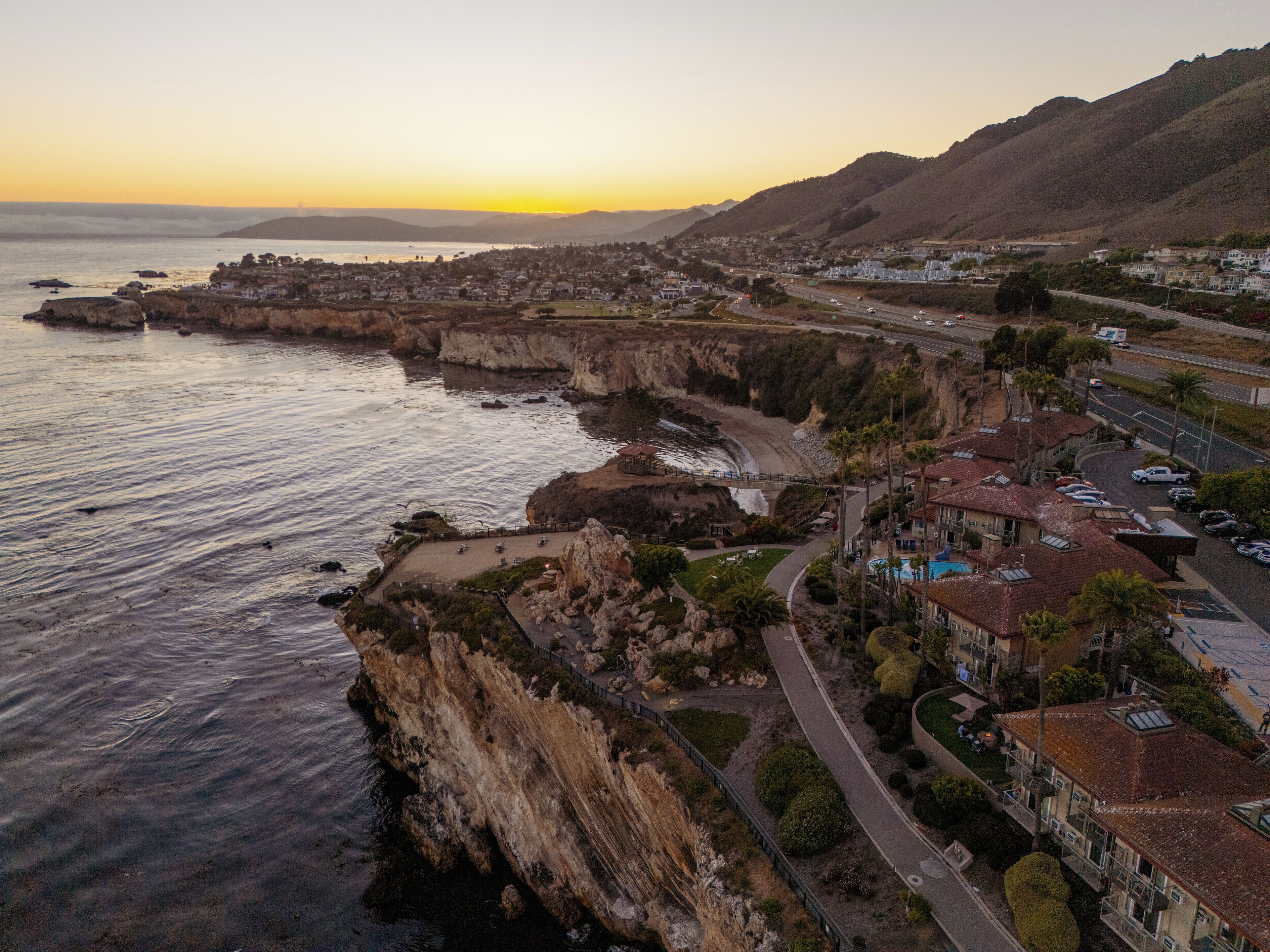 A coastal town with a prominent cliffside, a main road, and residential buildings.
