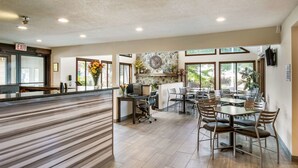 A spacious indoor area with a reception desk, multiple tables and chairs, and large windows providing natural light. - Quality Inn Bloomsburg (Bloomsburg)