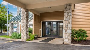 A building entrance with stone pillars, a glass door, and a small garden area. - Quality Inn Bloomsburg (Bloomsburg)
