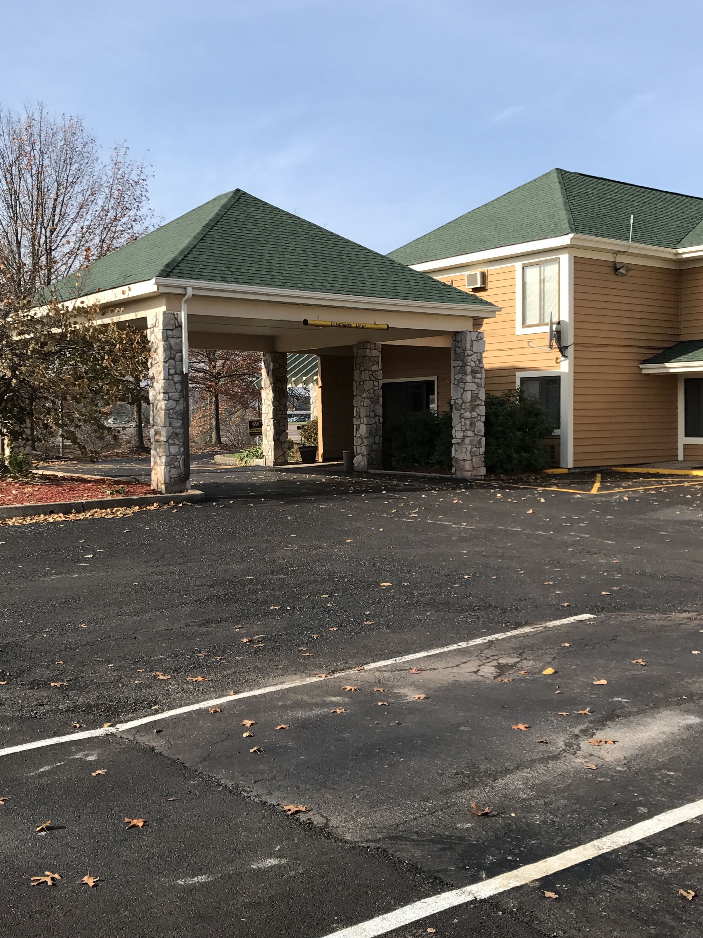 A building with a covered entrance and a parking lot.