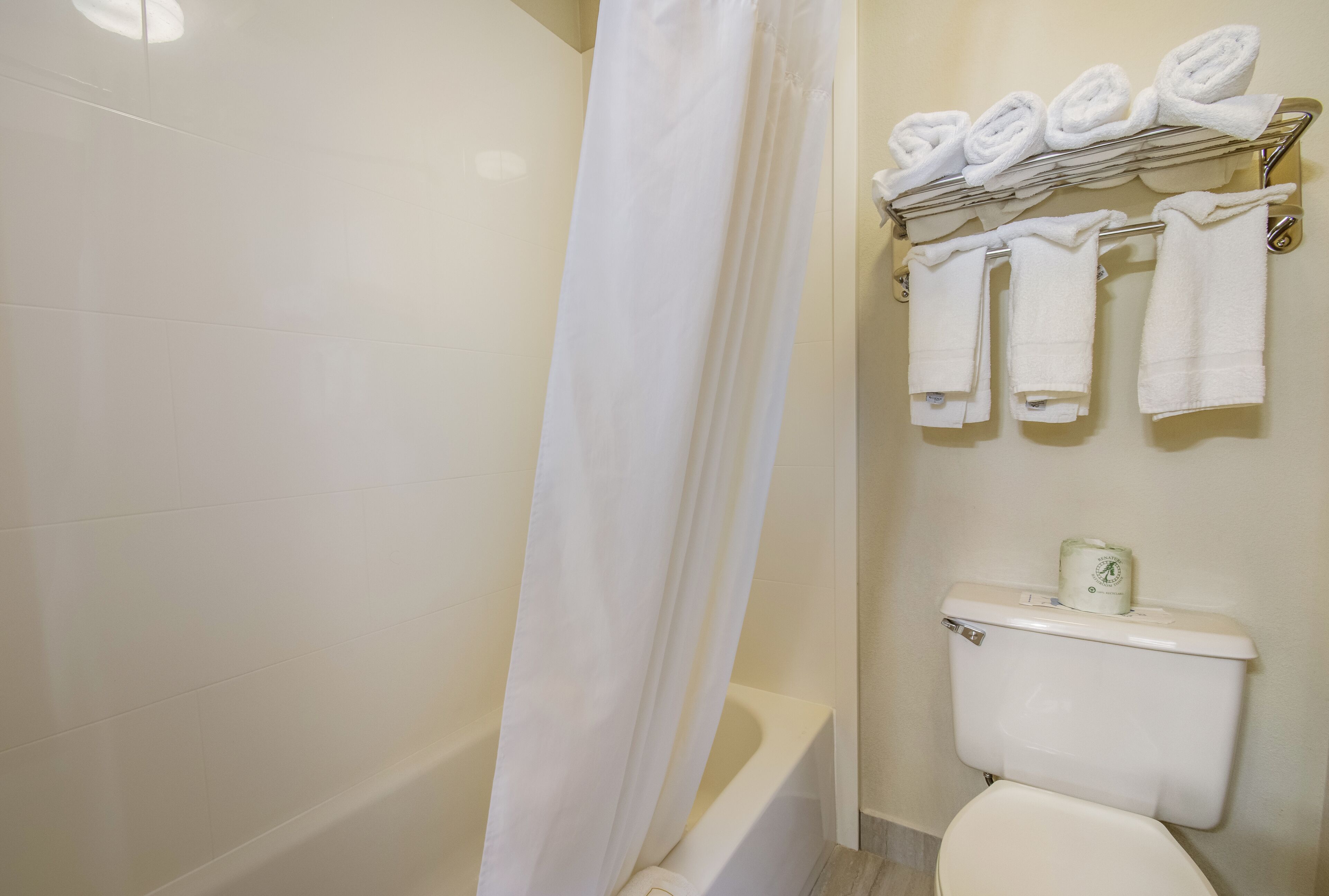 Un baño con bañera, inodoro y toallero con toallas dobladas.