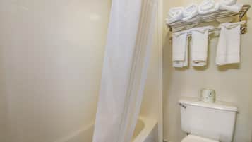 Un baño con bañera, inodoro y toallero con toallas dobladas.