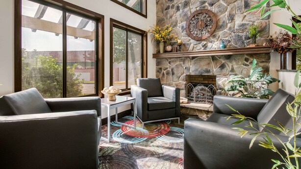 A modern living room with a stone fireplace, comfortable seating, and large windows. - Quality Inn Bloomsburg (Bloomsburg)