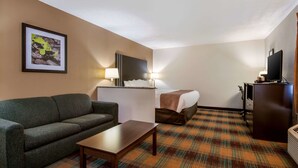 A hotel room with a sofa, a bed, a desk, a television, and a framed picture on the wall. - Quality Inn Bloomsburg (Bloomsburg)
