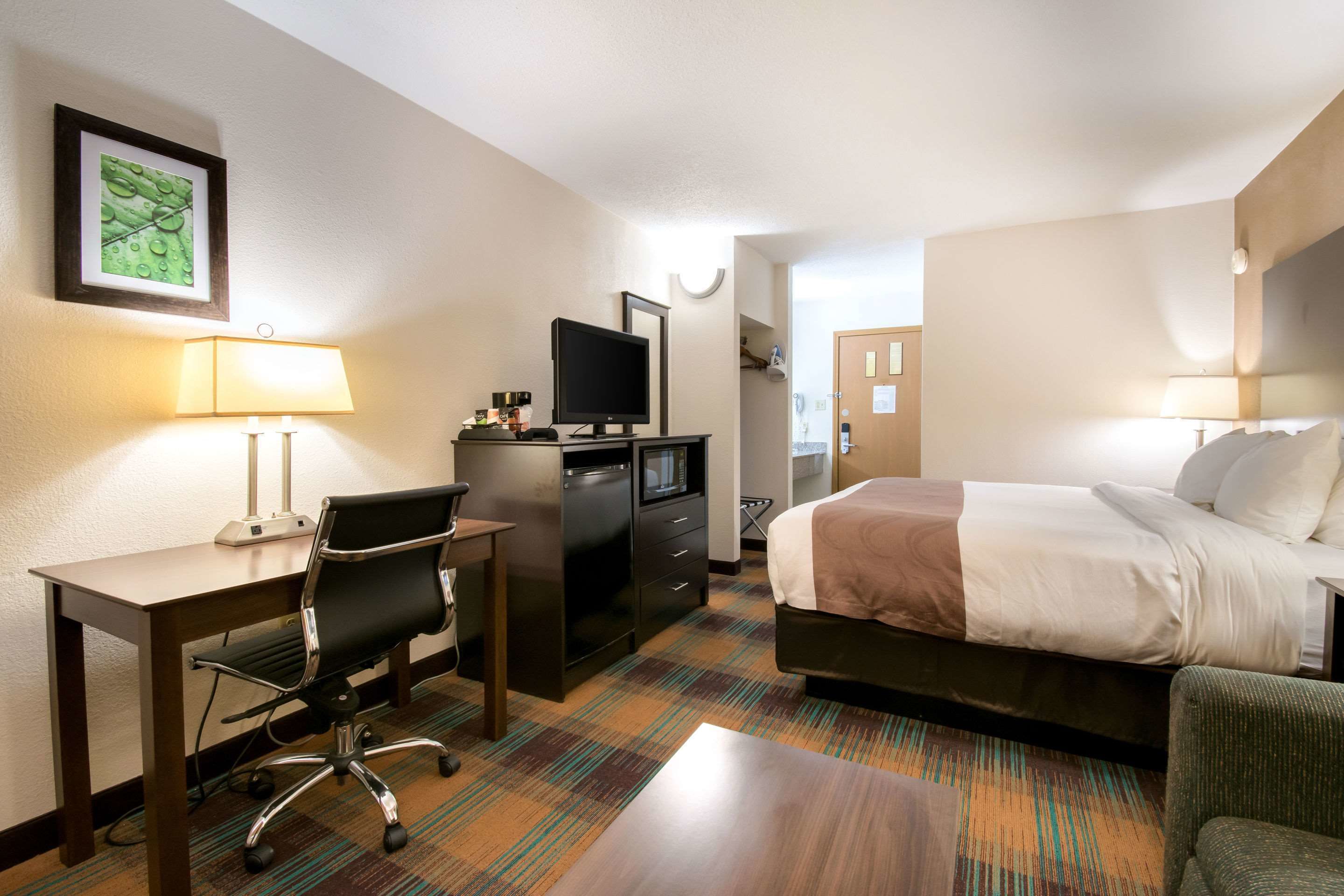 Ein Hotelzimmer mit Bett, Schreibtisch, Stuhl und Fernseher.
