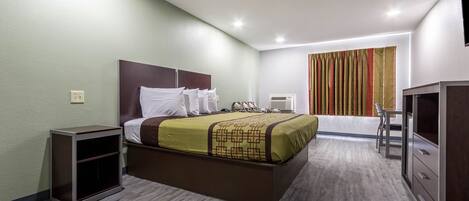 Una habitación de hotel con cama, mesita de noche, armario y ventana con cortinas.