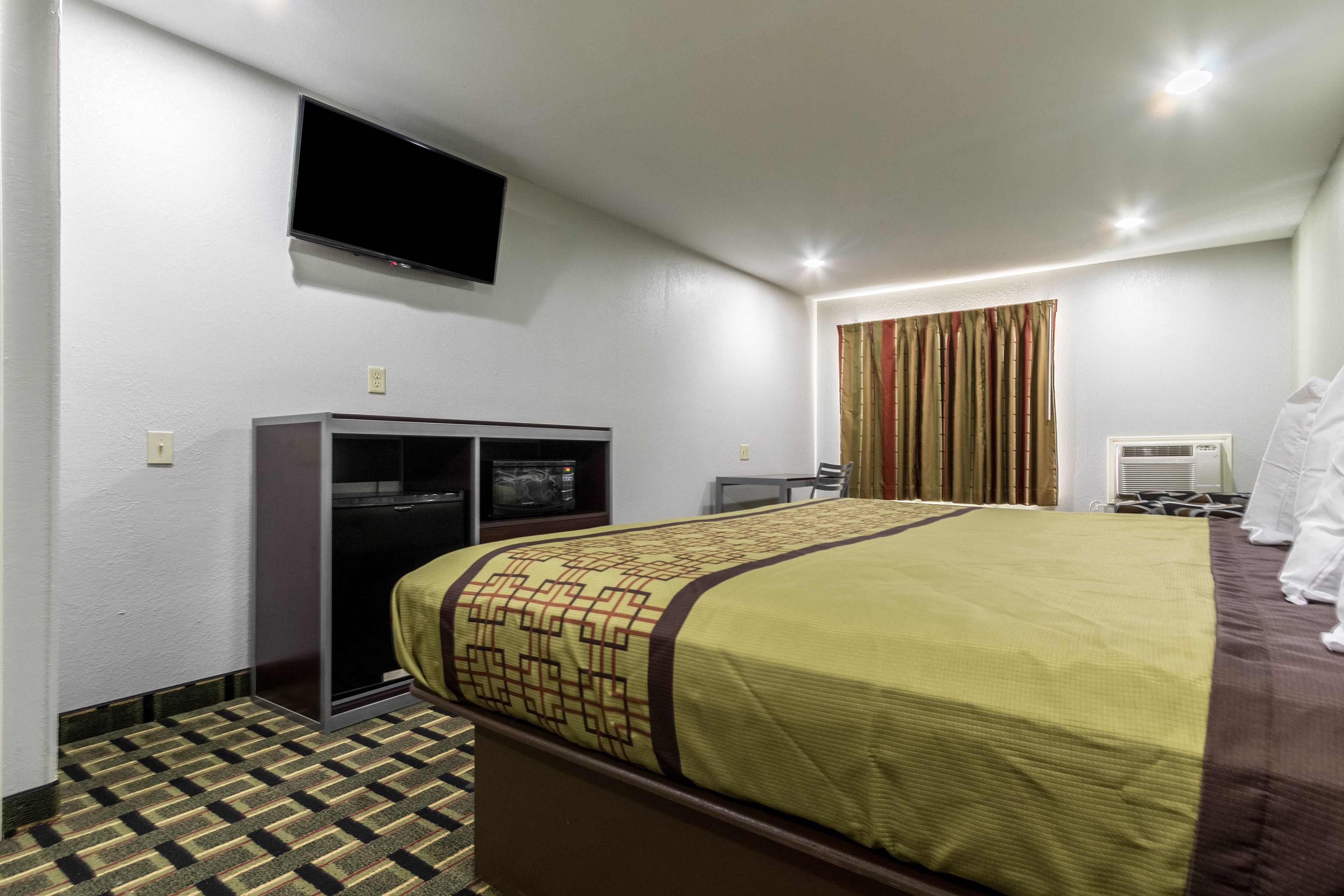 A hotel room with a bed, a television, a desk, and a wardrobe.