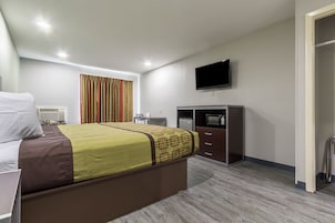 Una habitación de hotel con cama, escritorio, televisor y armario.