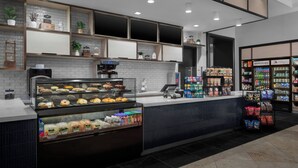 A bakery counter with baked goods, a coffee machine, and a refrigerated section with beverages.
