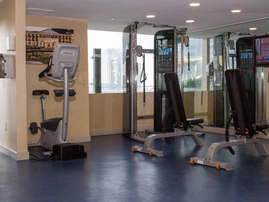 A gym with exercise equipment, a water dispenser, and a large window with a city view.