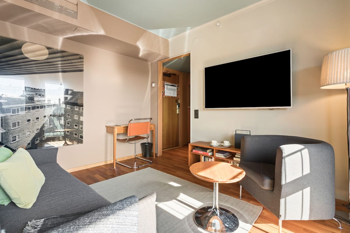 Una sala de estar moderna con un sofá, una mesa de centro, un televisor montado en la pared y una lámpara.
