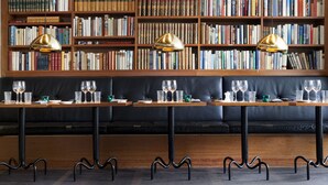 Een bibliotheek met boekenplanken, een lange tafel met glazen en een zwarte leren bank.