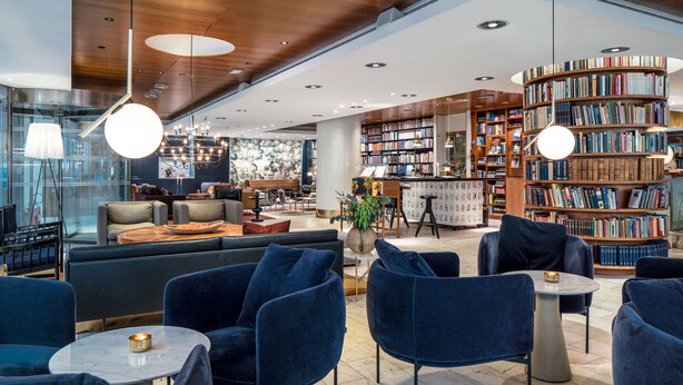 Een moderne bibliotheek met zitgedeeltes, boekenkasten en een open haard.