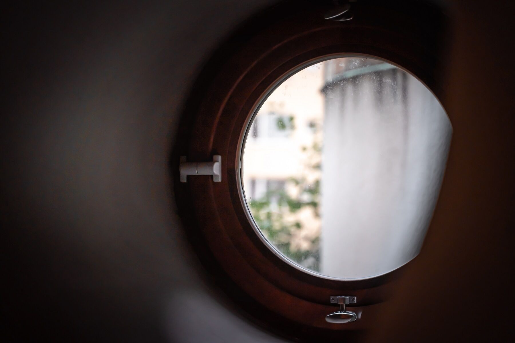 A round window with a metal latch, likely part of a door or wall.