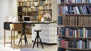 Una biblioteca con scaffali, un portatile su un tavolo e un vaso decorativo.