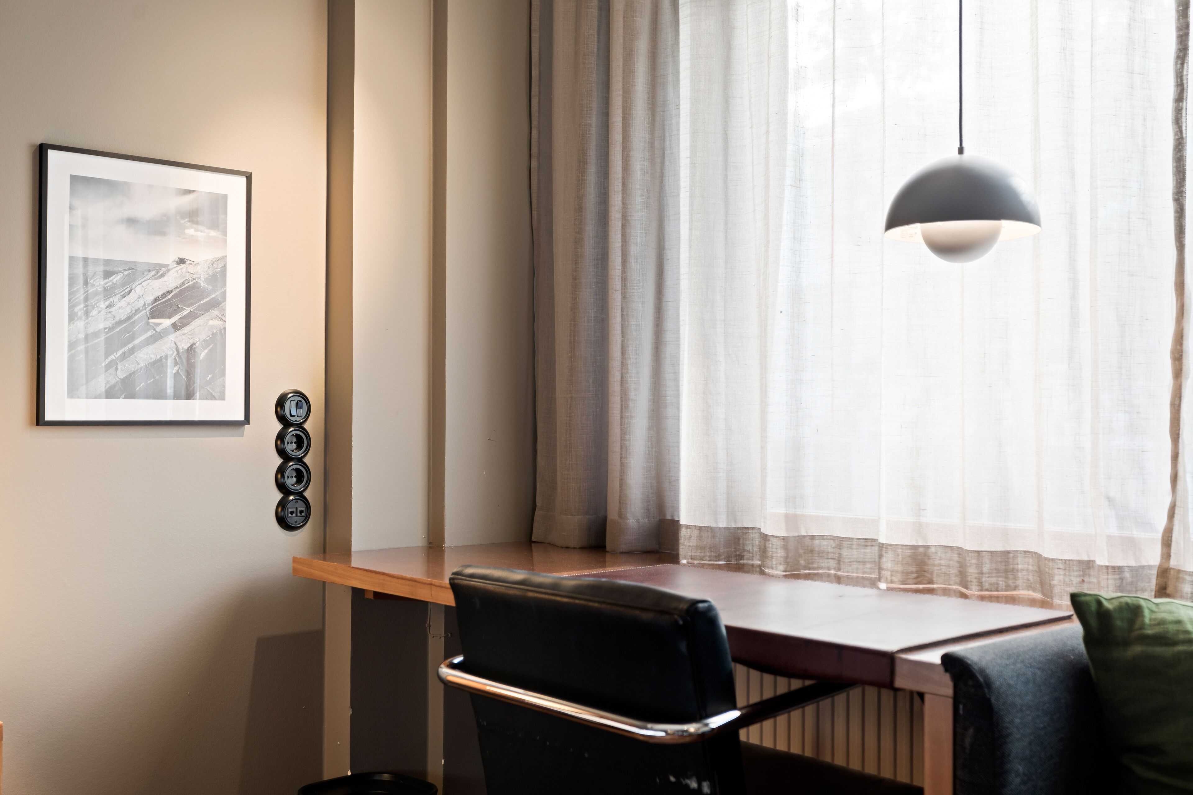 A room with a desk, chair, and a hanging pendant light.
