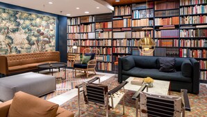 Een gezellige bibliotheek met een grote boekenkast, comfortabele zitplaatsen en een decoratief schilderij.