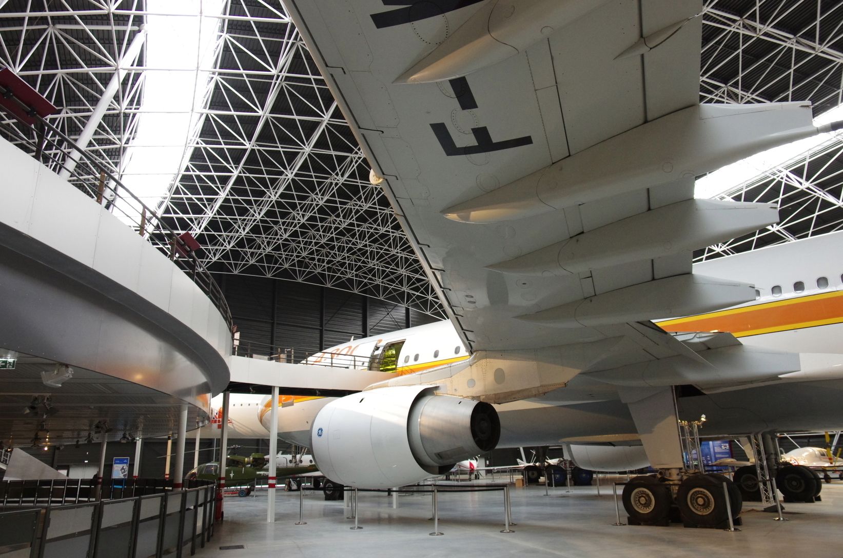 A large aircraft with visible structural details and a high ceiling with a metal framework.
