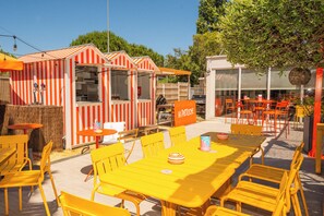 A restaurant with outdoor seating, a grill, and a striped building.