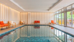A swimming pool with chairs and a view of the outdoors.