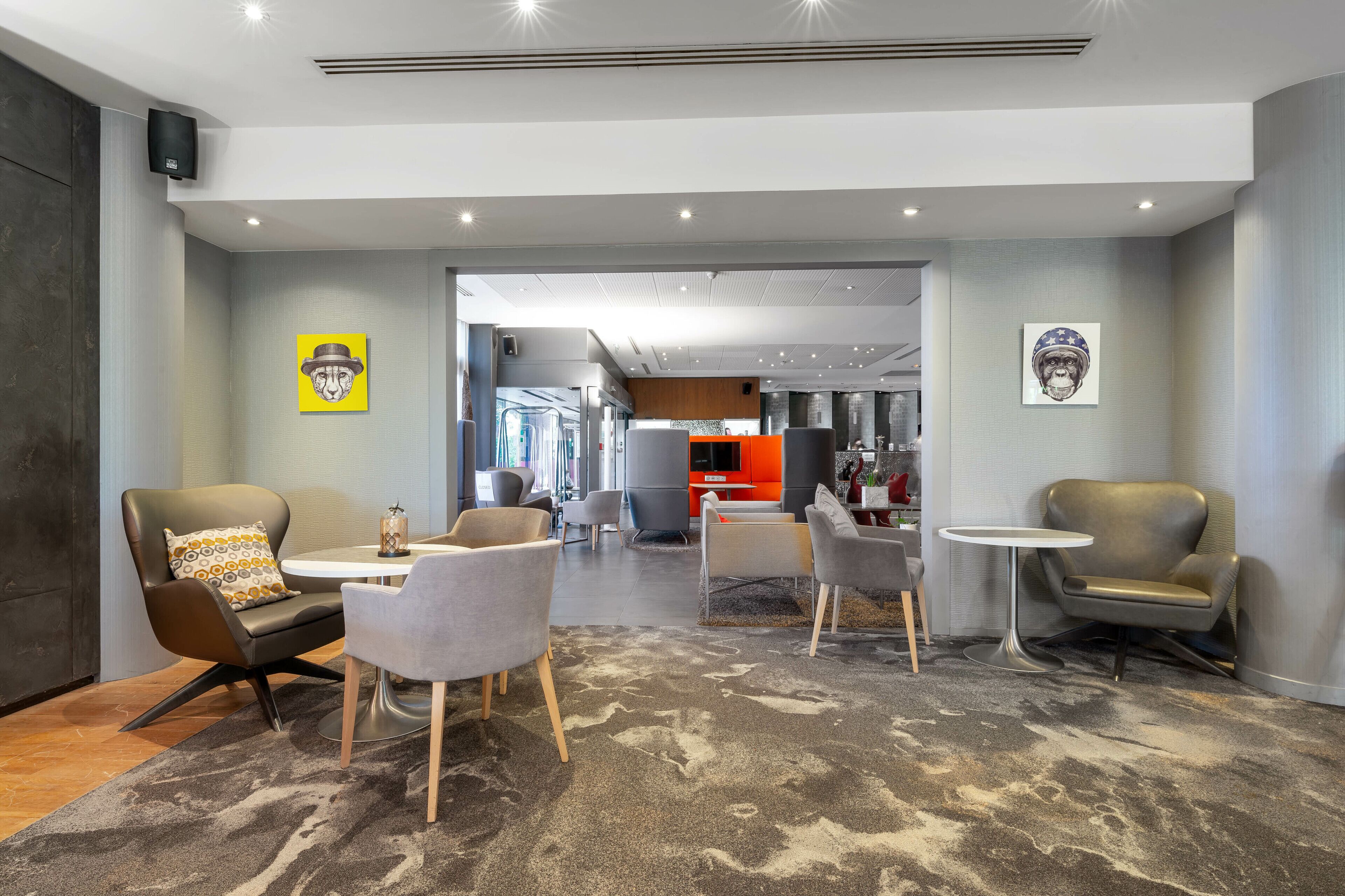 A modern lounge area with leather armchairs, a round table, and a patterned carpet.