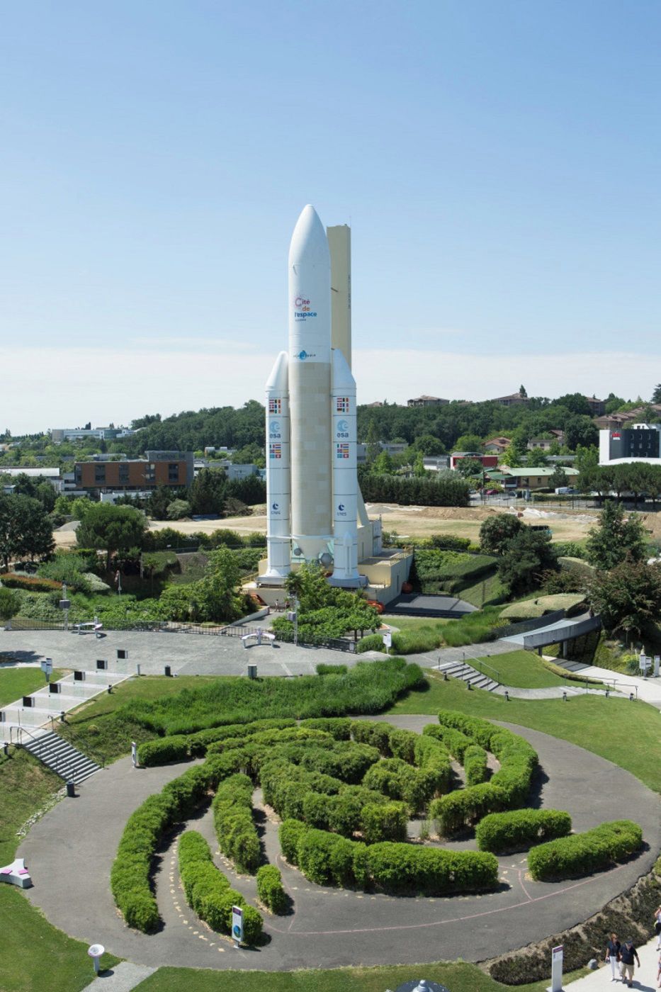 A space shuttle on a launch pad with a landscaped garden in the foreground.