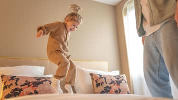 Family-friendly room with a simple design, featuring a bed with a headboard and floral-patterned pillows.