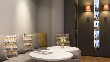 A modern lounge area with a sofa, two round tables, and a wall-mounted shelf with bottles.