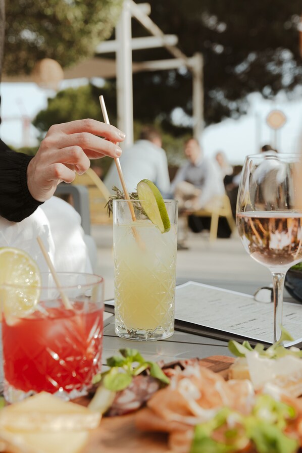 A table with drinks and food, a person holding a straw, and a menu.