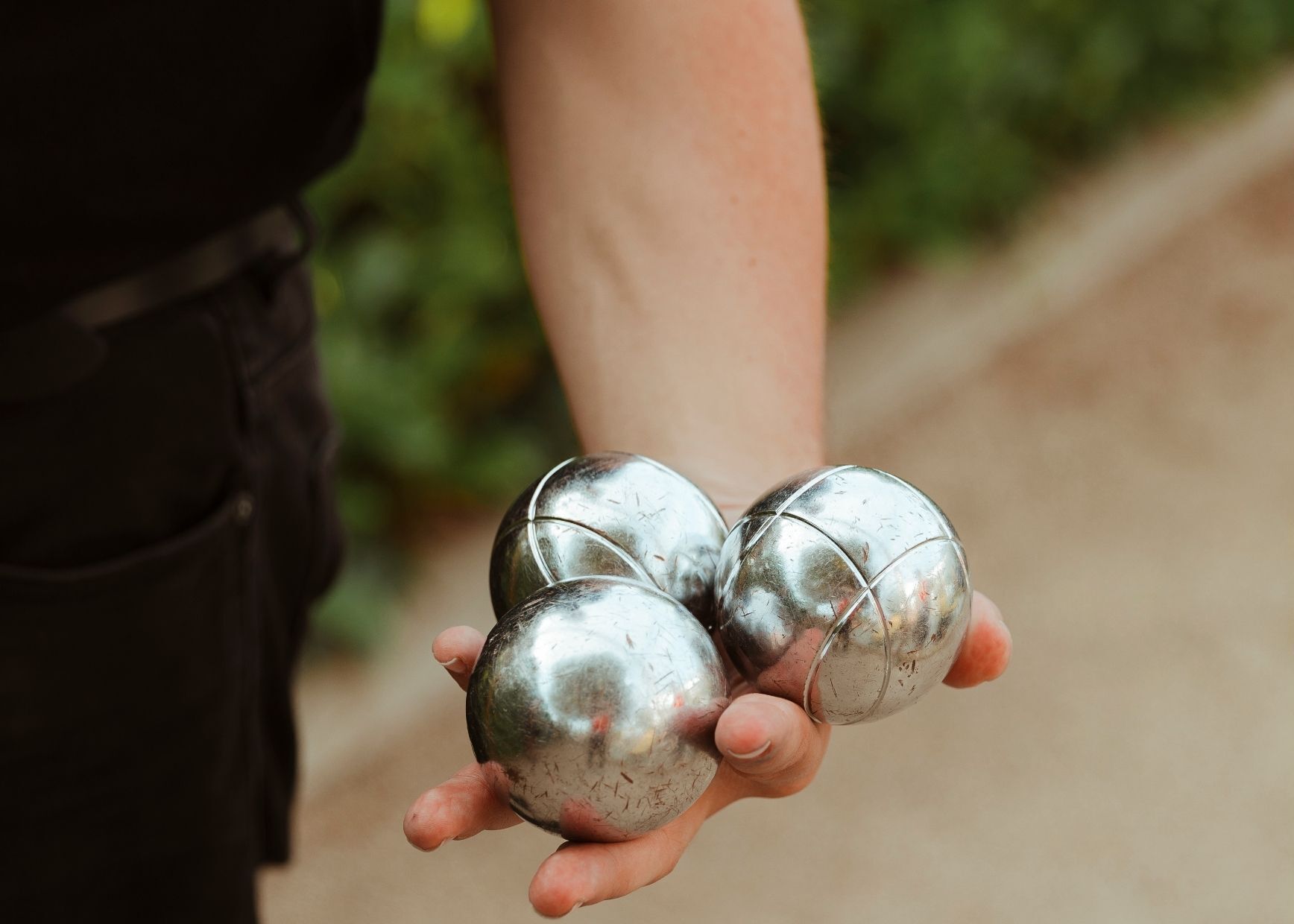 A person holding three metallic spheres.