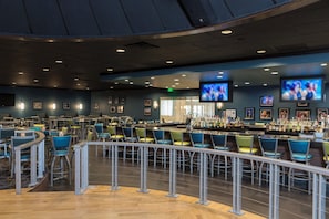 A bar area with multiple seating arrangements, a bar counter, and overhead televisions. - Holiday Inn Cleveland-S Independence by IHG (Independence)